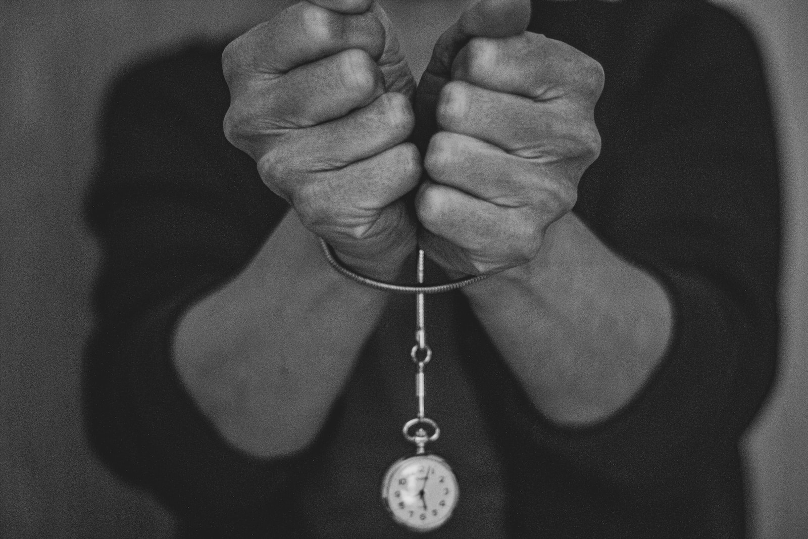 grayscale photo of person holding round pendant necklace